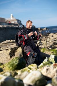 Professional advertising shot showing a man in full diving gear sat on rocks at south gare, Redcar. Shot by professional northeast advertising photographer Cal Carey.