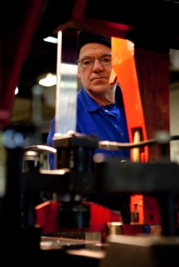 Professional industrial photographer showing an engineer slightly obscured by industrial equipment in the foreground. Shot by professional northeast industrial photographer Cal Carey.