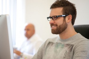 Professional commercial advertising shot showing a man smiling, looking at his computer which is just entering the left side of the frame. Shot by professional northeast commercial advertising photographer Cal Carey.