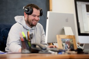 Professional advertising photography shot showing a VIA Creative worker sat at his desk, working on the computer, laughing. Shot by professional northeast advertising photographer Cal Carey.