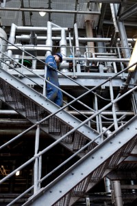Professional industrial photography shot showing a greenergy worker walking down a pair of stairs at their Biodiesel refinery site. Shot by professional northeast industrial photographer Cal Carey.