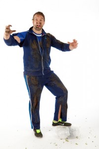 Professional advertising photography shot showing a man dressed as a PE teacher but with rips in clothes and covered in mud. Shot on a white background. Shot by professional northeast advertising photographer Cal Carey.