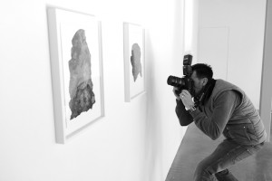 Black and white behind the scenes shot showing Cal Carey Photographer shooting art on the walls.