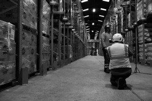 Black and white behind the scenes photography shot showing Cal Carey Photographer photographing a man with an industrial surrounding.
