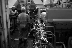 Black and white behind the scenes show showing Cal Carey Photographer engaging with a man posing for a photograph with industrial surroundings.