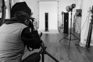 Black and white behind the scenes photography showing Cal Carey Photographer shooting an Ebac water cooler on a white background in his studio.