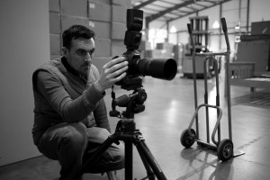 Black and white behind the scenes photography shot showing Cal Carey Photographer looking through his DSLR shooting the subject.