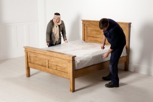Behind the scenes photography shot showing two people sorting out a bed ready to be shot.