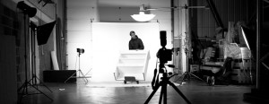 Black and white behind the scenes shot showing somebody wheeling a piece of cabinet off the photography set.