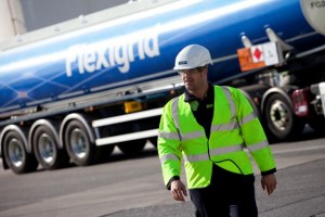 A commercial industrial photograph for Greenergy of a worker stood in front of a Greenergy tanker and the Greenergy logo wearing Flexigrid branded personal protective equipment Greenergy is A company that helps business customers create revenue by controlling carbon dioxide emissions through carbon asset management. Shot by Cal Carey industrial photographer.
