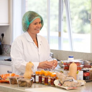 Corporate people photography shot of a smiling chef in a kitchen preparing food. Shot by professional northeast photographer Cal Carey.