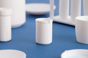 Professional product photography shot showing a small piece of white labware, a small container, on a blue background. Shot by professional northeast product photographer Cal Carey.