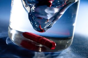 Professional product photography shot showing a magnet in a beaker of water and the liquid is being attracted to the magnet which is captured with a very high shutter speed and flash. Shot by professional northeast product photographer Cal Carey.
