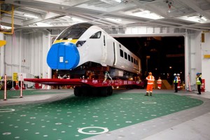 Professional industrial and transport shot of a Hitachi train being loaded out of the ship, with workers in high-visabilty clothing. Shot by professional north-east photographer Cal Carey.