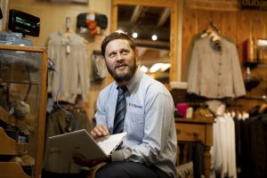 Professional commercial photography shot showing an Odyssey team member at a shop of a client on a laptop setting up odyssey software for them. Shot by professional northeast commercial photographer Cal Carey.