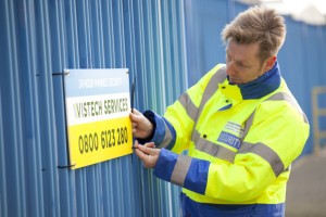 Professional commercial shot showing a Vistech security guard fixing a sign to a gated. Shot by professional northeast commercial photographer Cal Carey.