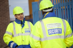 Professional commercial shot showing two Vistech security guards in high-visibility coats and hard hats. One guard with his back to camera and the other looking towards the other guard face on with the camera. Shot by professional northeast commercial photographer Cal Carey.