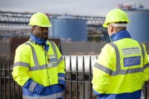 Professional commercial shot of two Vistech security guards in high-visabilty clothing and hard hats. Out of focus industrial location in the background. Shot by professional northeast commercial photographer Cal Carey.