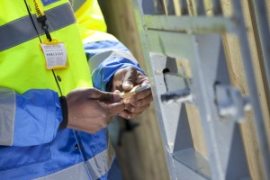 Professional commercial shot showing a security guards hands fastening a padlock onto a gate, about to lock it. Shot by professional northeast commercial photographer Cal Carey.
