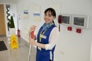 Professional commercial shot of a cleaner looking to the camera smiling, posing with a mop and in Vistech uniform. Shot by professional northeast commercial photographer Cal Carey.