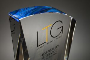 Professional product photography shot showing a glass award that's manufactured by Crystal Galleries, on a blue background. Shot by professional northeast product photographer Cal Carey.