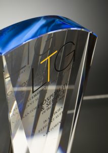 Professional product photography shot showing a glass award that's manufactured by Crystal Galleries, on a blue background. Shot by professional northeast product photographer Cal Carey.