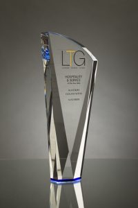 Professional product photography shot showing a glass award that's manufactured by Crystal Galleries, on a blue background. Shot by professional northeast product photographer Cal Carey.