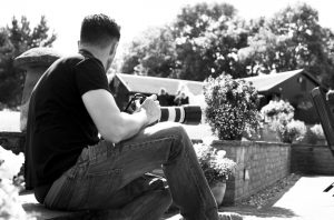 Black and white behind the scenes shot showing Cal Carey on a shoot with camera on hand ready to shoot.
