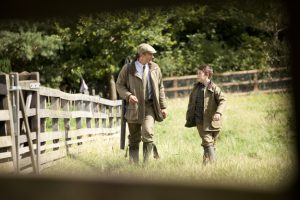 Professional commercial photography shot showing a boy and his father walking in a field with hunting clothing on. Shot by professional northeast advertising photographer Cal Carey.
