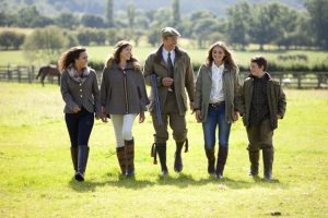 Professional advertising photography shot showing a family of 5 walking in a field, laughing with each other. Shot by professional northeast advertising photographer Cal Carey.