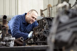 Professional industrial photography shot showing a motor part being removed from an engine by an operative. Shot by professional northeast industrial photographer Cal Carey.