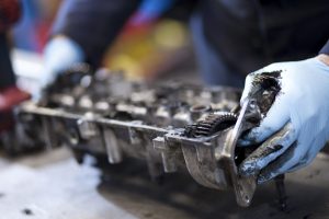 Professional industrial photography shot showing a motor part being removed from an engine with hands in the frame covered with blue gloves. Shot by professional northeast industrial photographer Cal Carey.