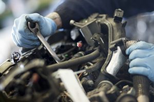 Professional industrial photography shot showing a motor part being removed from an engine with hands in the frame covered with blue gloves. Shot by professional northeast industrial photographer Cal Carey.