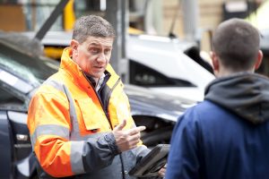 Professional industrial photography shot showing a man from Morgan's in a high-vis coat holding a device whilst talking to another worker at Morgan's. Shot by professional northeast industrial photographer Cal Carey.