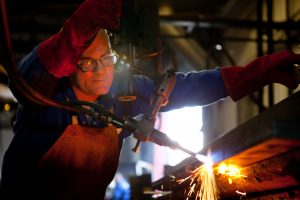 A portrait photograph of a Conmech engineer welding steel with sparks been given off. The engineer is wearing personal protective equipment. Shot by Cal Carey industrial photographer based in the north east UK.